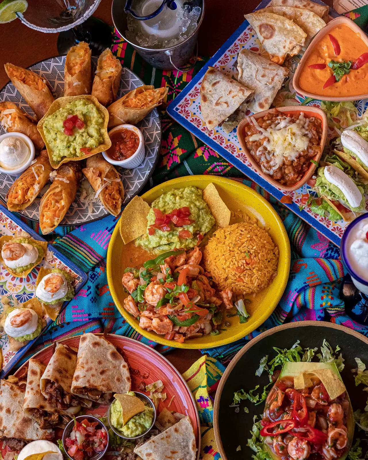 Mesa festiva com camarões, arroz mexicano, quesadillas, flautas e queso fundido