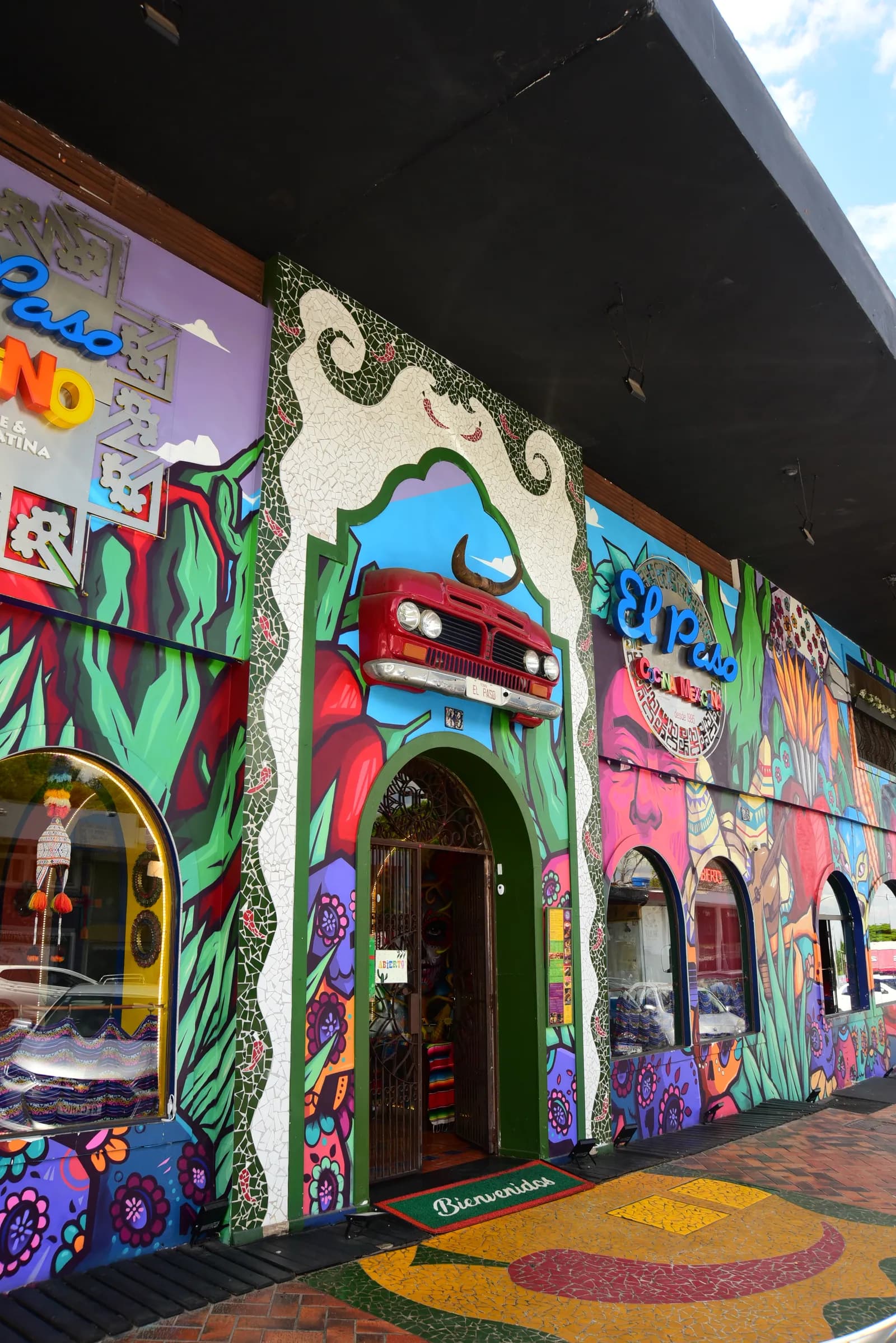 Fachada do El Paso Asa Sul coberta de murais coloridos, com o carro vermelho sobre a porta em arco