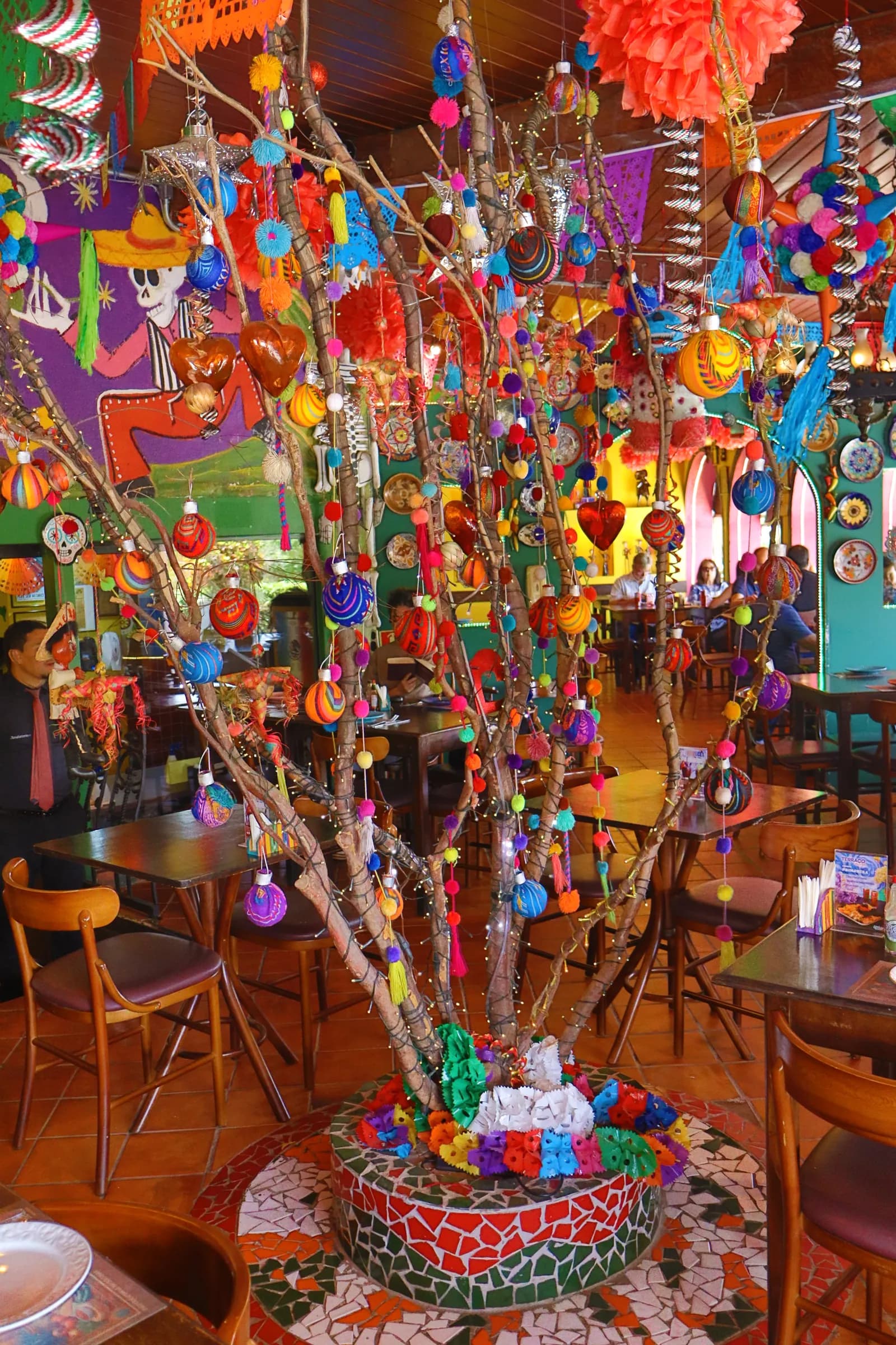 Árvore decorativa com enfeites coloridos no salão