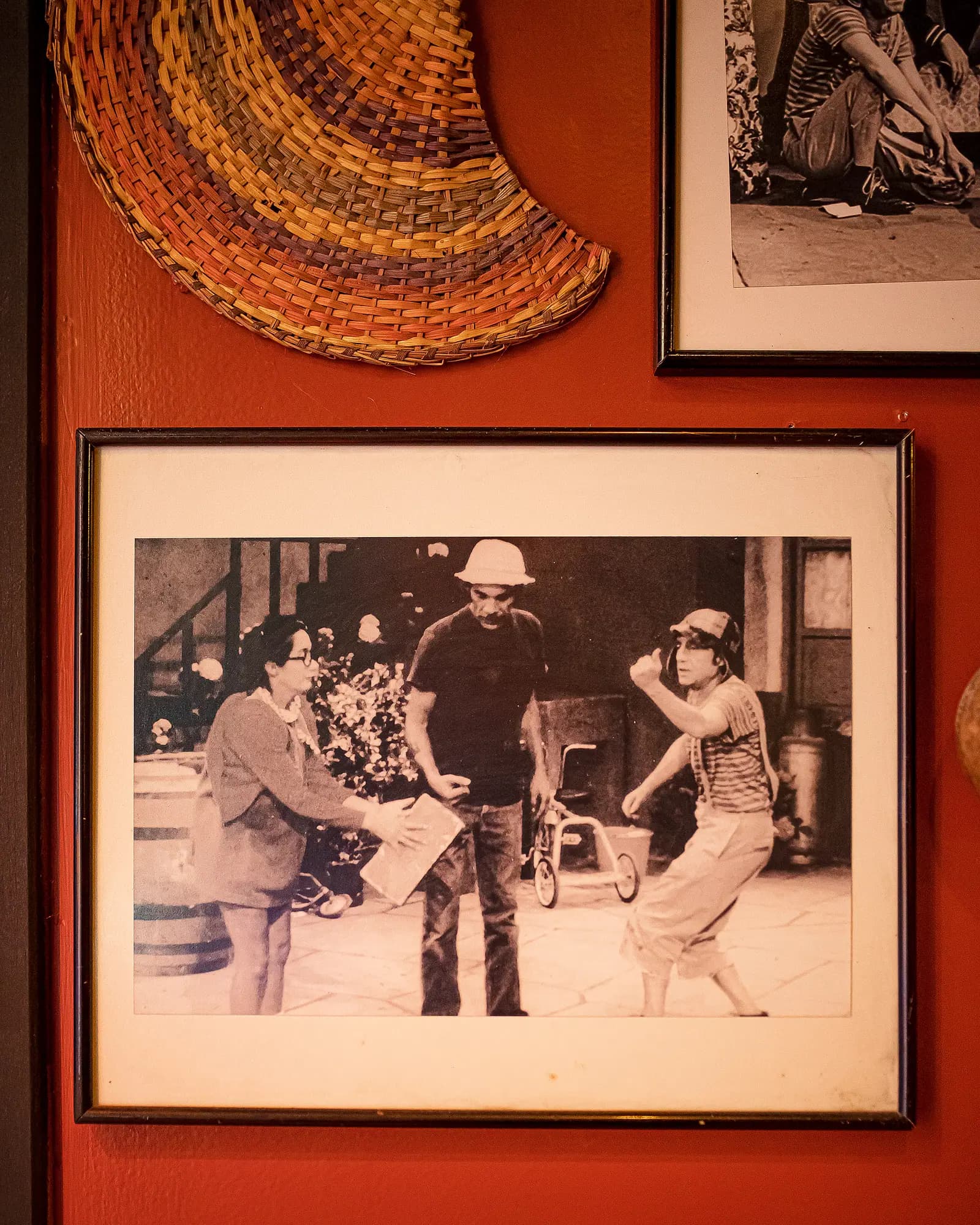 Parede vermelha com quadros do seriado Chaves e cesto de palha artesanal