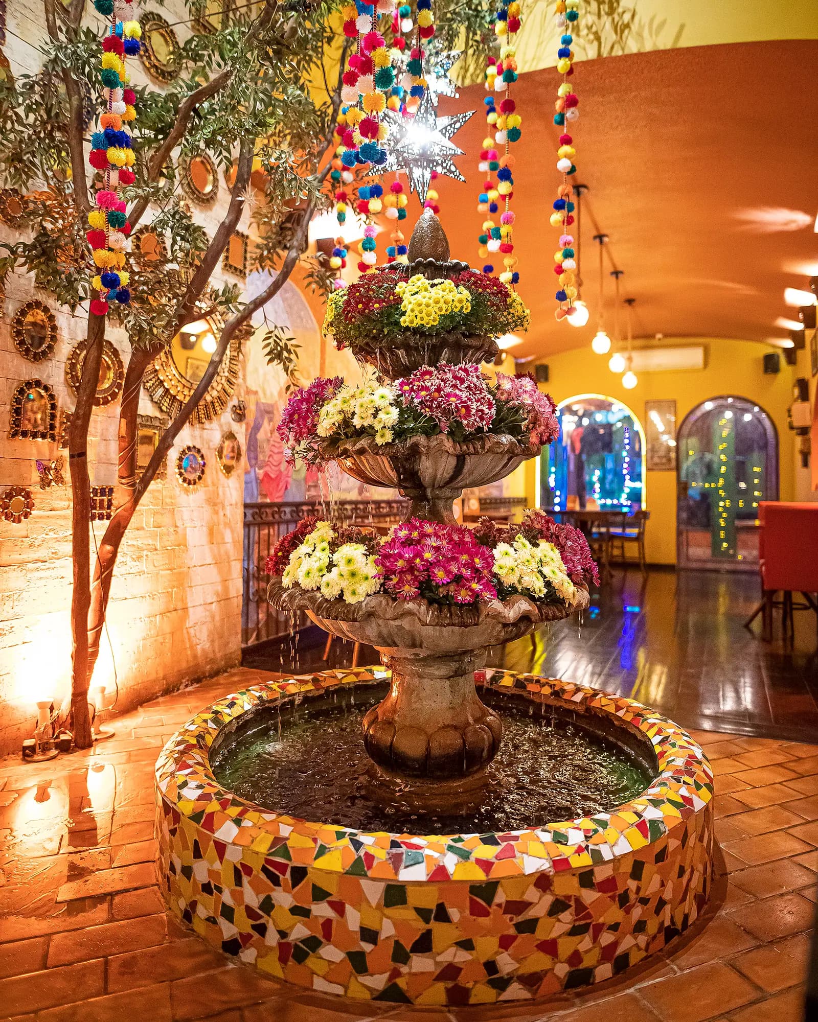 Fonte de pedra coberta de flores sob estrelas de lata e fitas de pompons no salão principal