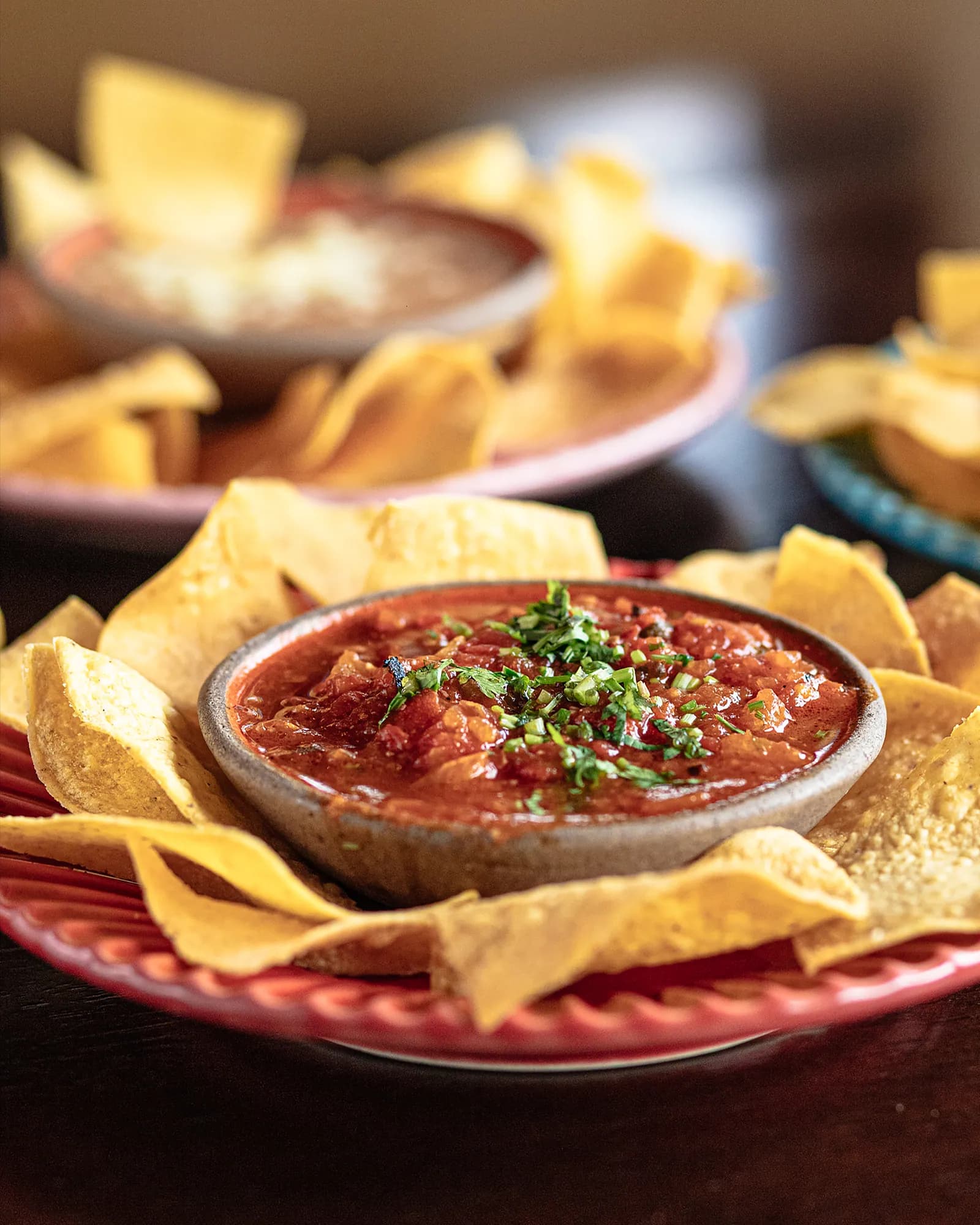 Salsa roja com coentro fresco e totopos em prato vermelho
