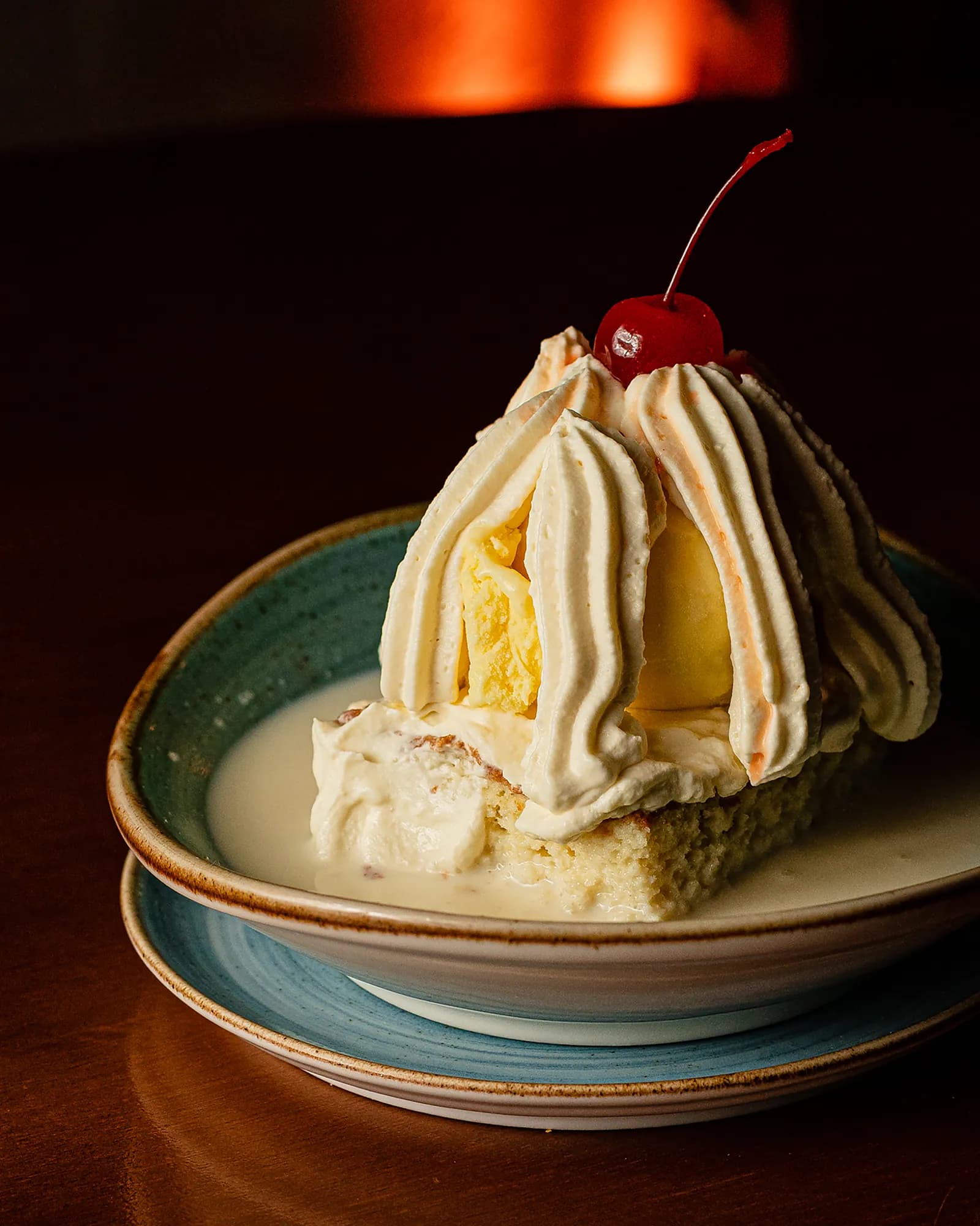 Bolo tres leches com chantilly e cereja em louça artesanal