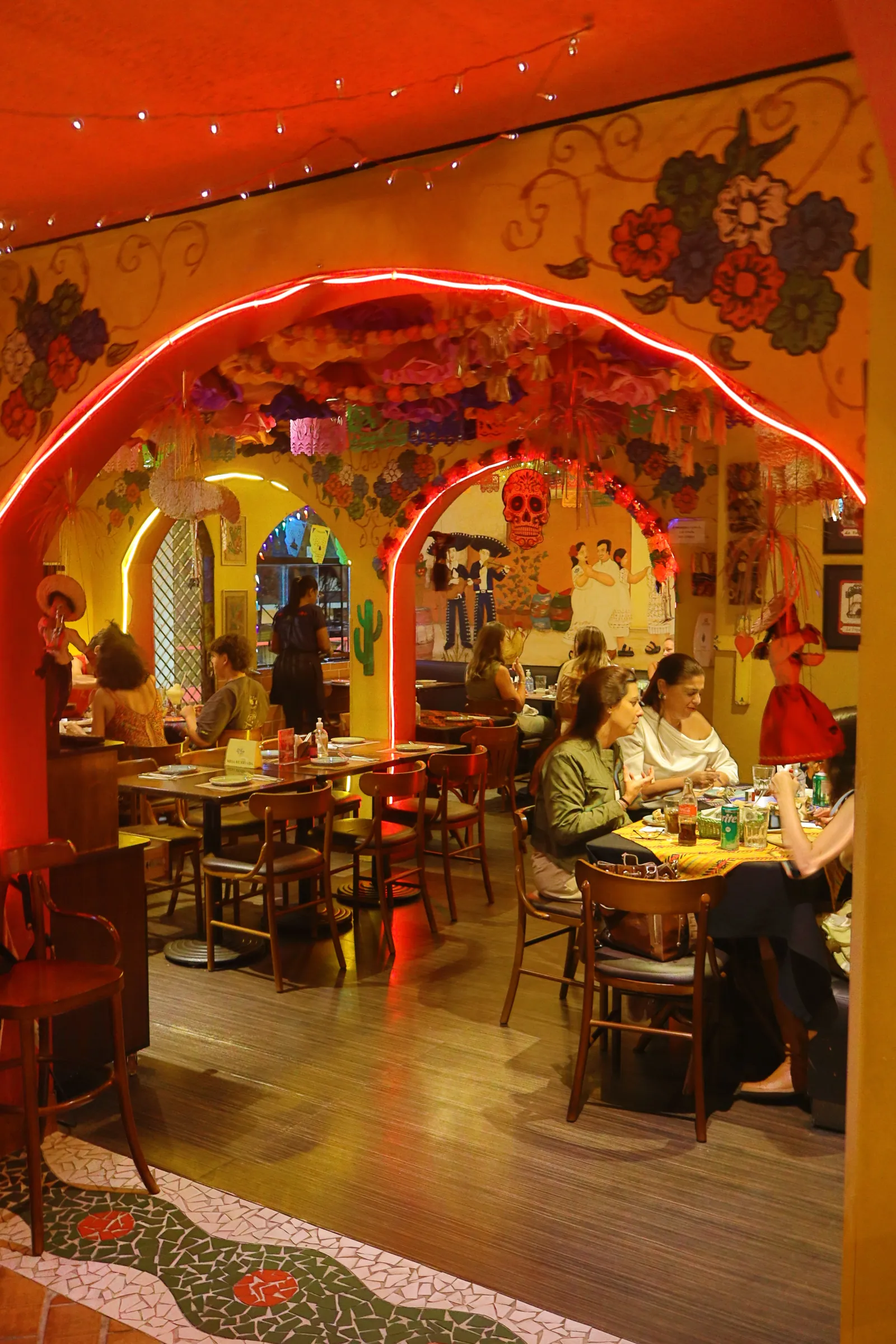 Salão movimentado com arco neon e mural de dançarinos
